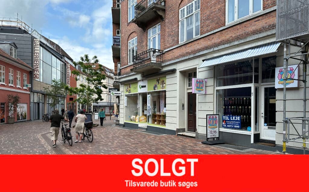 Slotsgade i Hillerød med butikken i den brogede husrække. Rødt solgt-banner er lagt oven på fotoet.