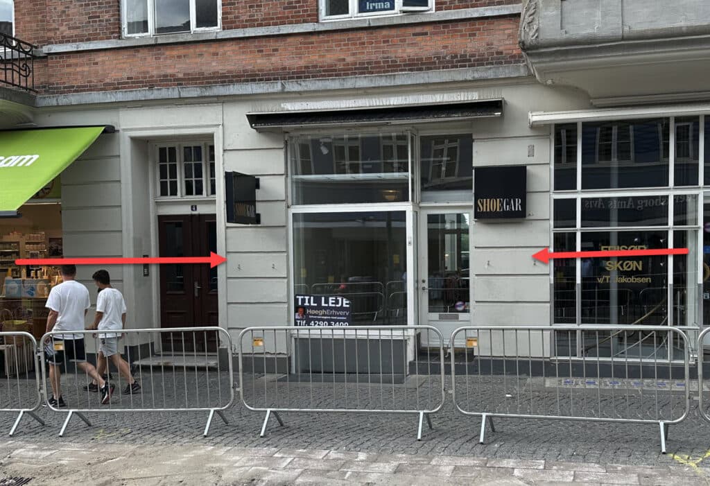 Gågaden i Slotsgade i Hillerød med forbipasserende foran butikkerne på en solskinsdag.